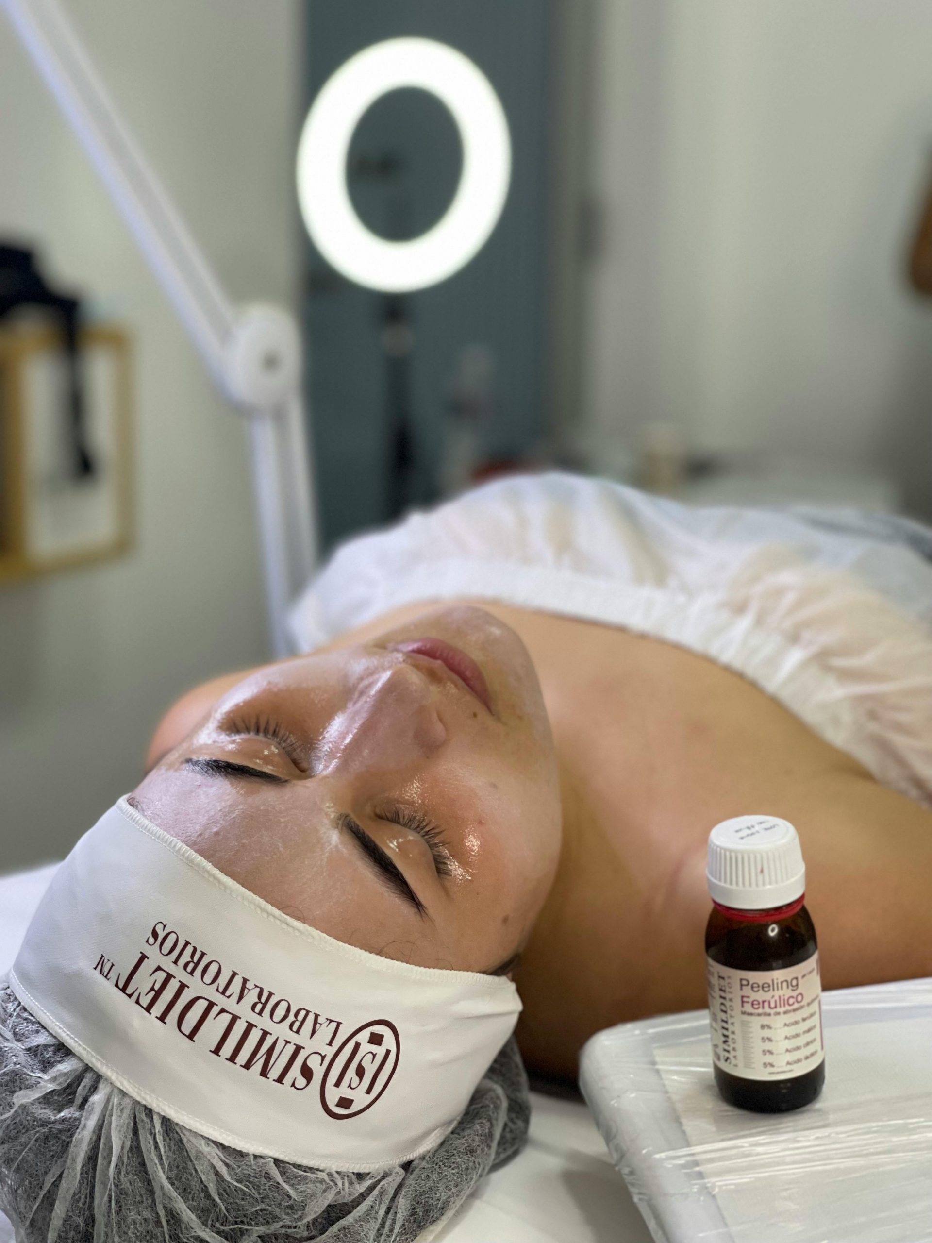 A woman relaxing during a facial peeling session featuring skincare products in a spa setting.
